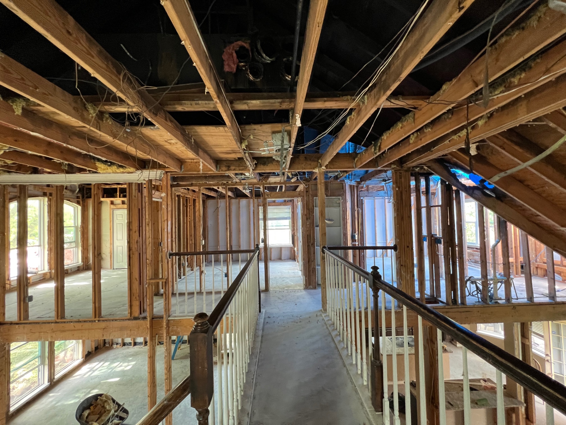 Second-floor walkway inside a two-story home gutted down to the framing